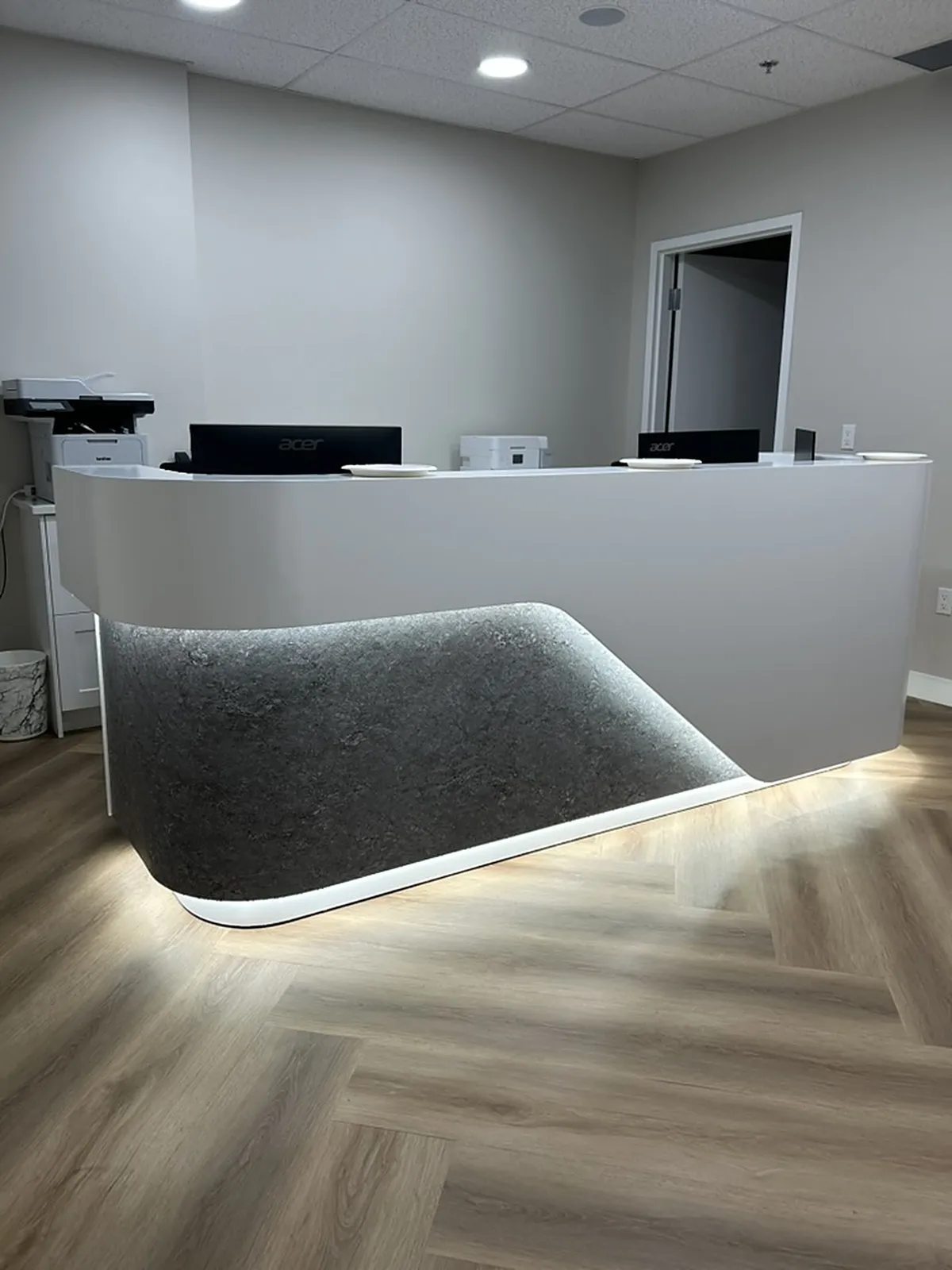 Curved white reception desk with grey felt panel and LED underglow