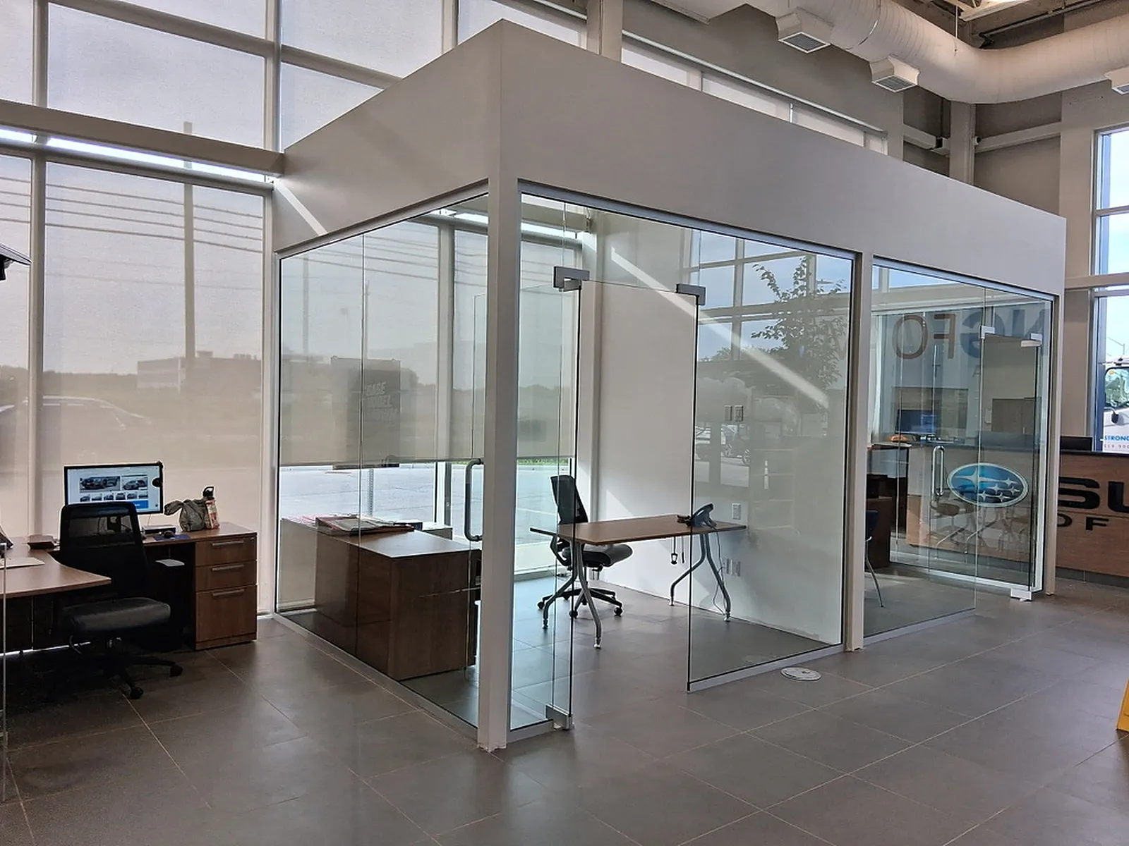 Glass-walled private offices along a bright open-plan floor